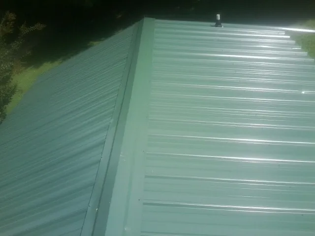 New green metal panels meeting at the ridge of a roof — Flat Roof Repair work by our crew in Kiln