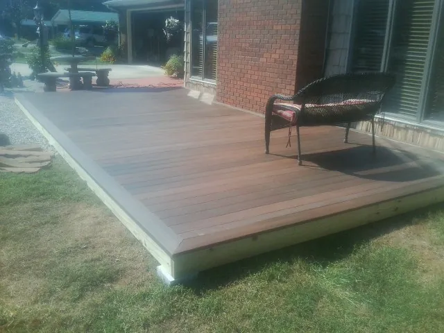 New wood deck and wicker chair beside a brick house in Kiln
