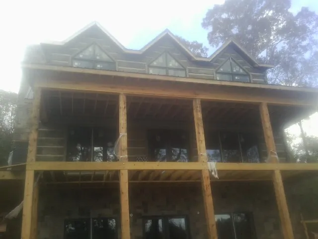 Dormers and porch framing on a large log home under construction — Roof Coating work by our crew in Kiln