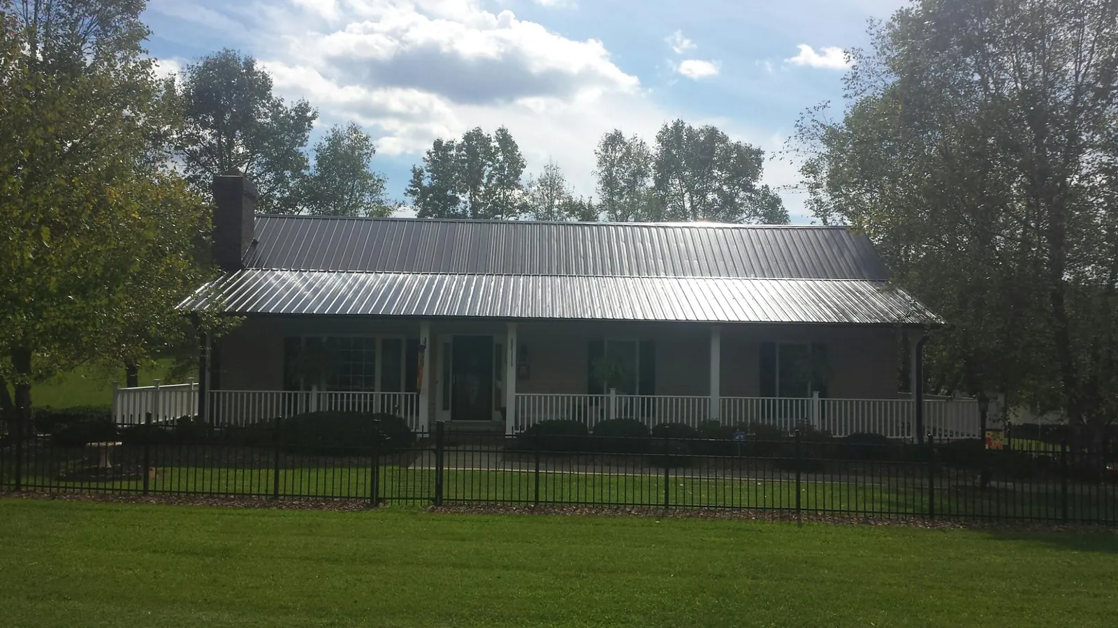 Gray metal roof on a brick ranch with a full width front porch — Gutter Guard Installation work by our crew in Kiln