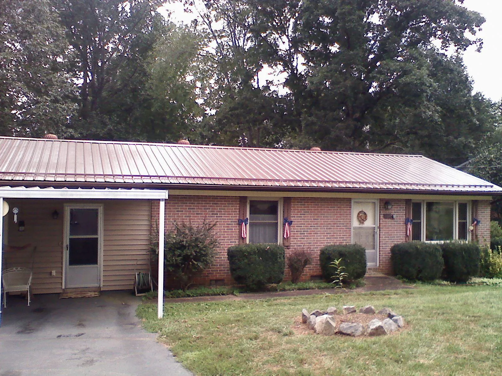 Bronze metal roof and carport on a brick ranch home — Roof Repair work by our crew in Kiln